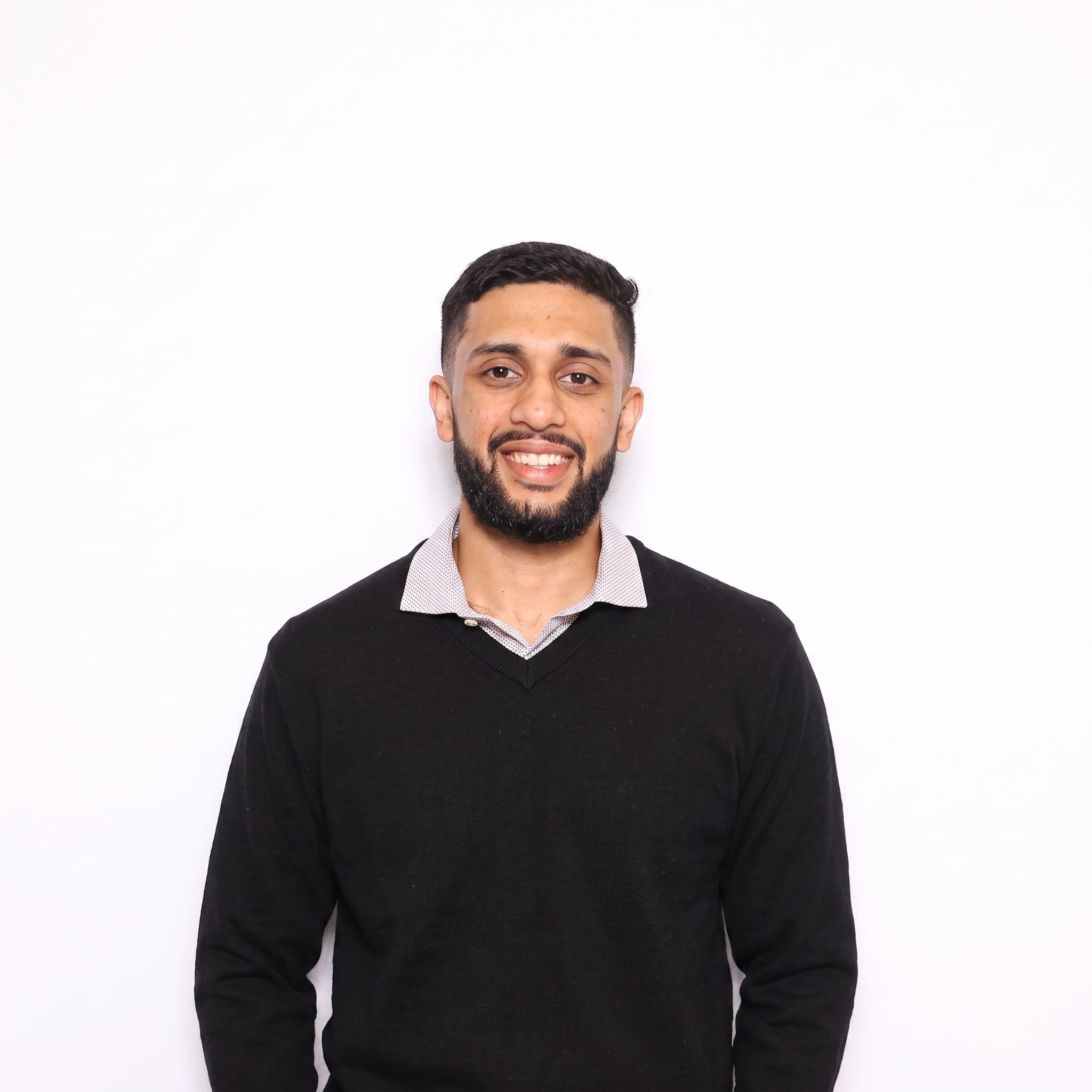 Vipul Sharma smiling in a portrait photo, wearing a black sweater over a collared shirt.